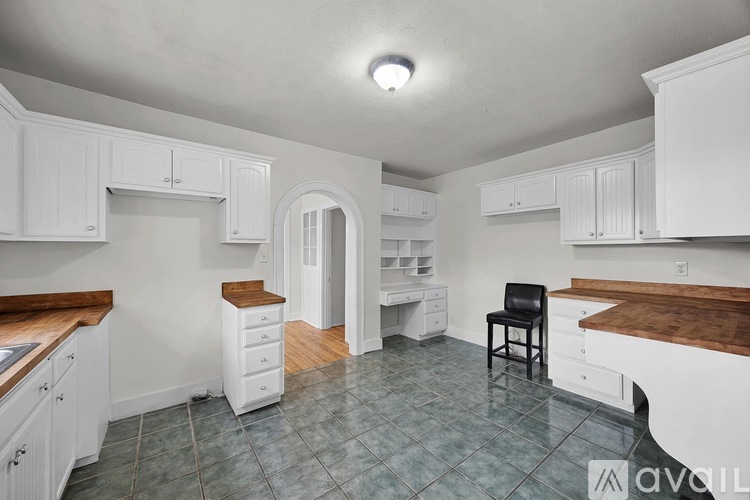 A kitchen with white cabinets and a tile floor.