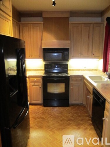 A kitchen with wooden cabinets and black appliances.