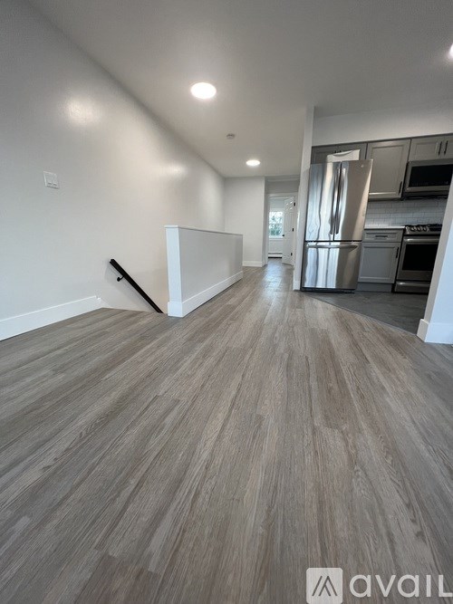 A spacious room with wooden flooring and a white wall.