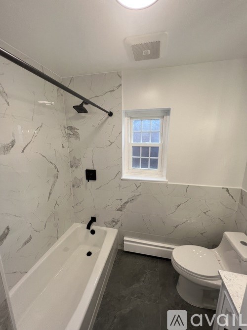 A bathroom with a marble wall and a white bathtub.