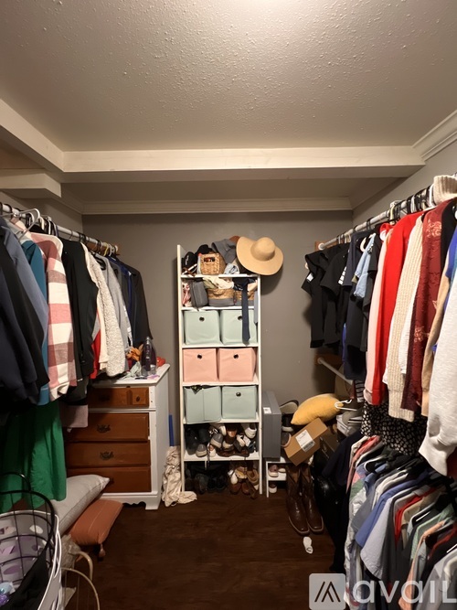 A room with a closet full of clothes and a shelf with shoes.