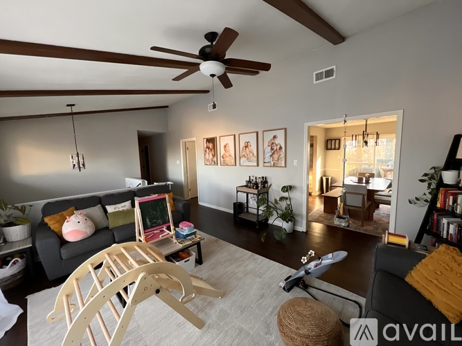 A living room with a grey couch and a wooden rocking chair.