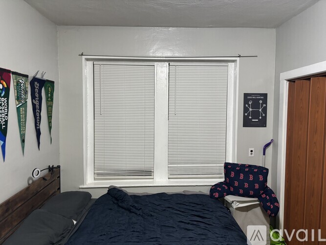 A bedroom with a bed, pillow, and a window with blinds.
