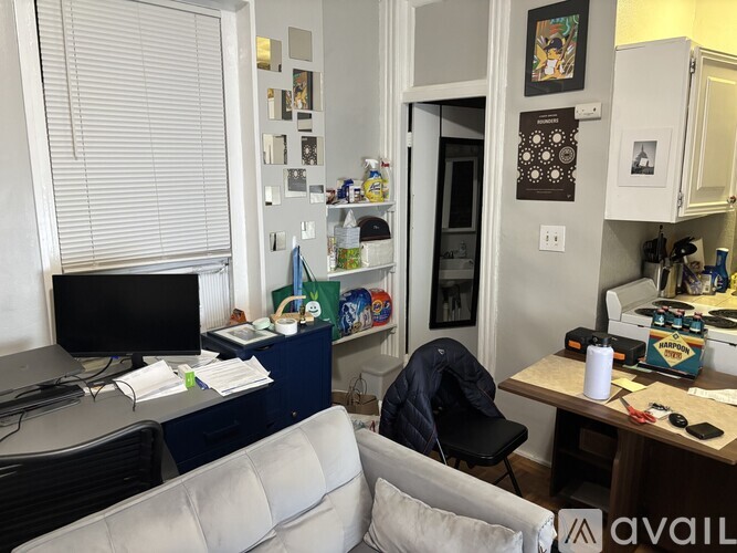 A small apartment with a kitchen, living room, and a desk with a computer.
