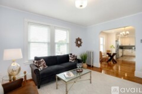 A living room with a black couch and a glass coffee table.