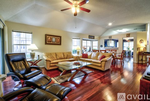 A living room with a black leather chair and a wooden floor.