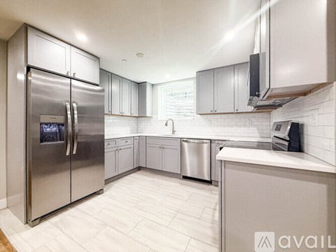 A modern kitchen with a stainless steel refrigerator and a white tile floor.