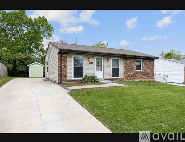 A house with a green shed and a white fence is for sale.