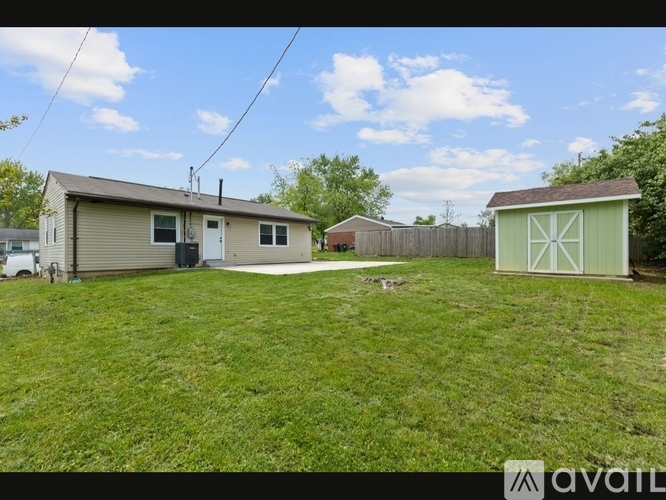 A grassy area with a house, a shed, and a fence.