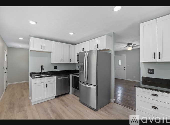 A kitchen with white cabinets and a stainless steel refrigerator.