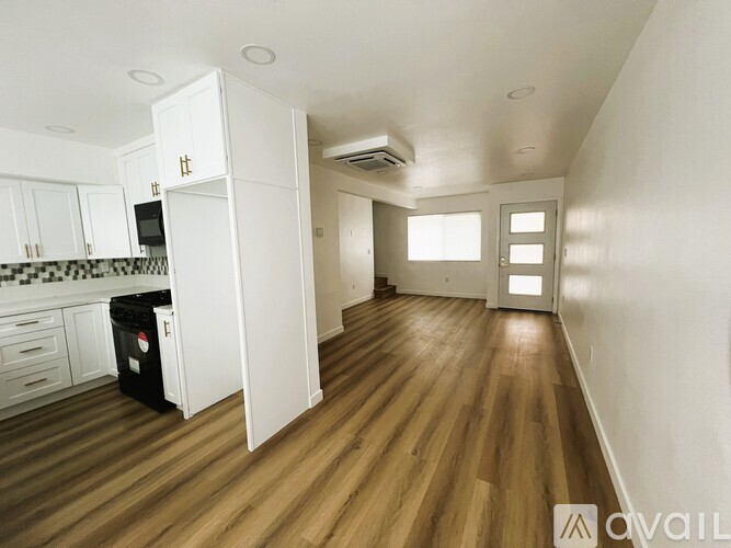 A kitchen with white cabinets and a black trash bin.