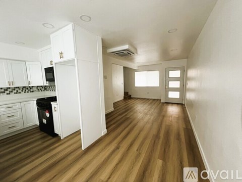 A kitchen with white cabinets and a black trash bin.