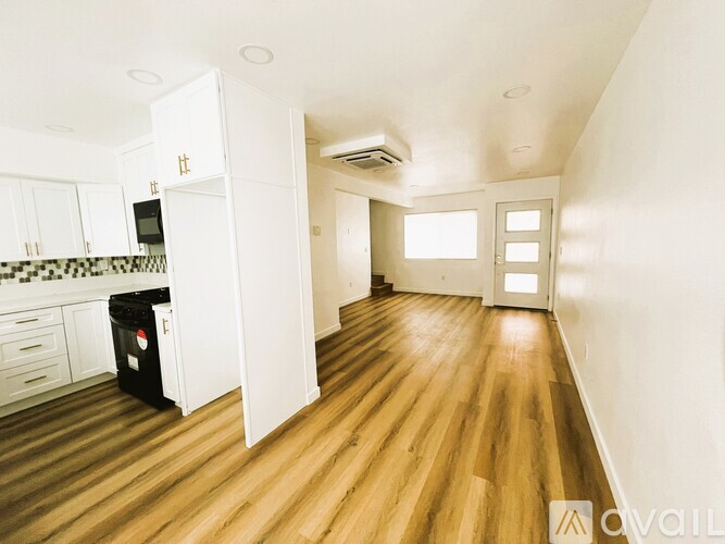 A kitchen with white cabinets and a black trash bin.