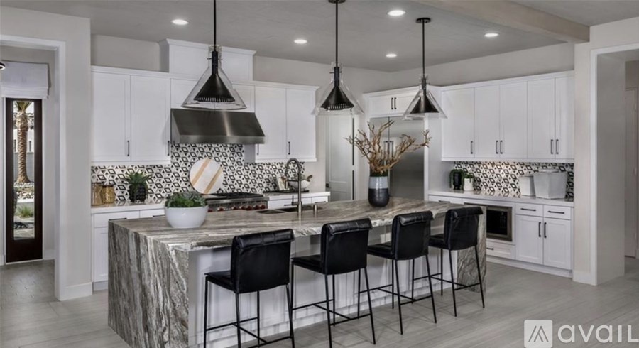 A kitchen with a marble island and black barstools.