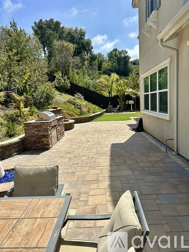 A patio with a table and chairs overlooks a pool and a wooded area.