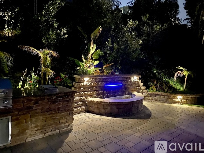 A garden with a hot tub and a stone wall.