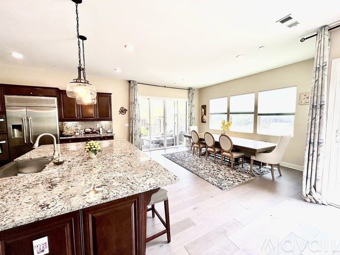 A kitchen with granite countertops and a dining area with a table and chairs.