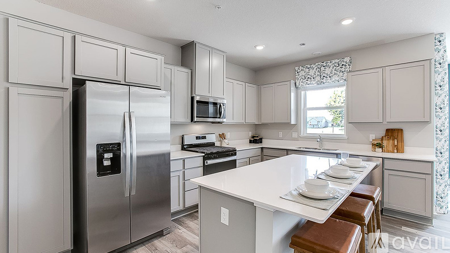 A modern kitchen with a refrigerator, microwave, oven, and a dining table with chairs.