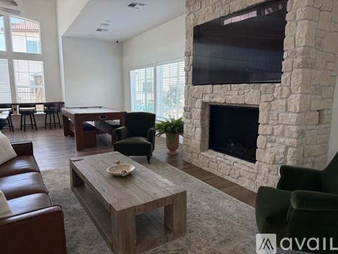 A living room with a stone fireplace and a flat screen TV mounted above it.