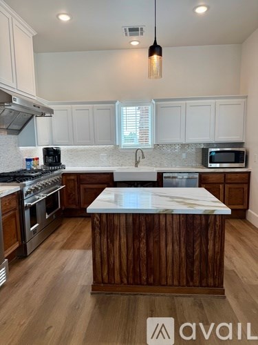 A kitchen with wooden cabinets and a marble island.