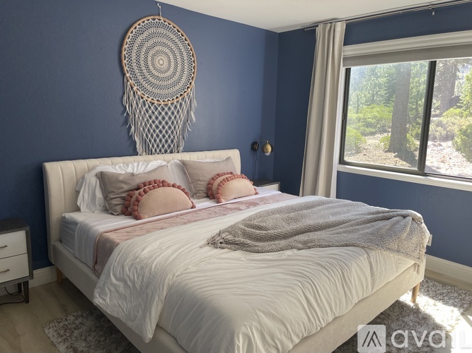 A bedroom with a white bed and a dream catcher hanging on the wall.