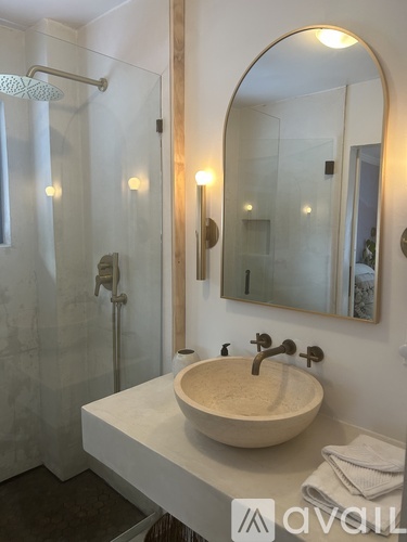 A bathroom with a sink, mirror, and shower.