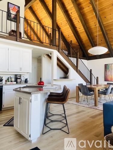 A kitchen with a wooden ceiling and a dining table with chairs.