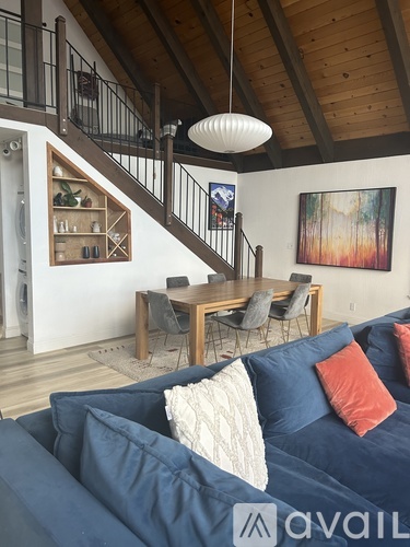 A living room with a blue couch and a wooden staircase.