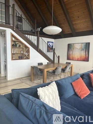 A living room with a blue couch and a wooden staircase.