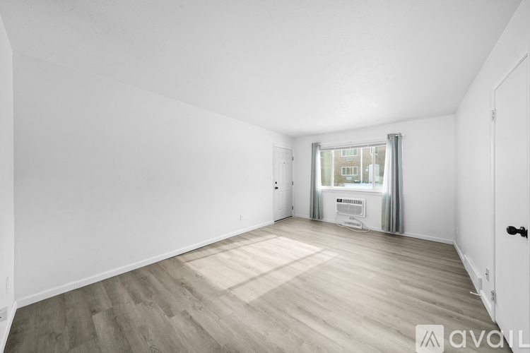 A spacious room with wooden flooring and white walls.