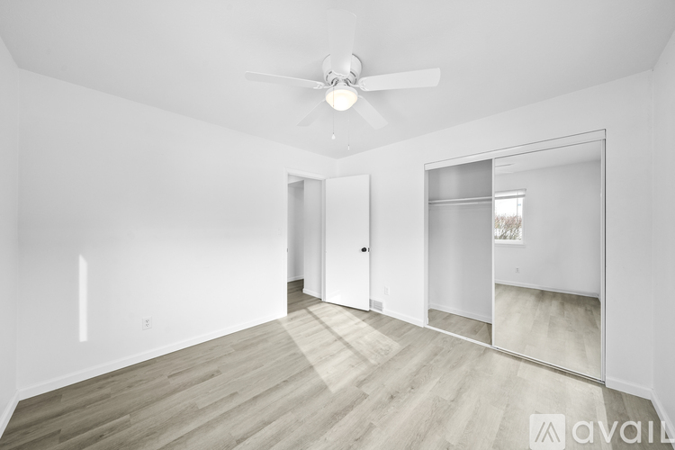 A spacious room with a ceiling fan and wooden flooring.