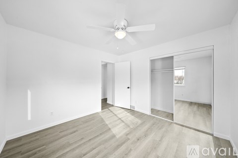 A spacious room with a ceiling fan and wooden flooring.