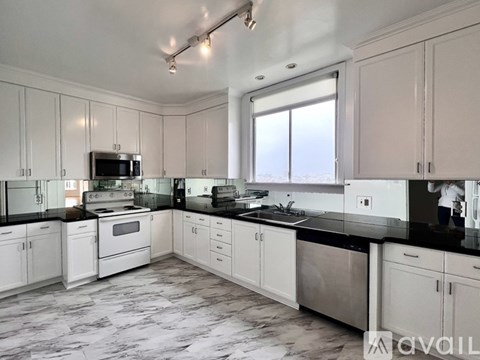 A kitchen with white cabinets and black countertops.