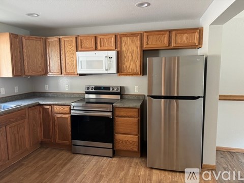 A kitchen with wooden cabinets and a stainless steel refrigerator.