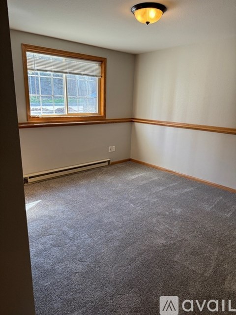 A room with a window and a carpeted floor.