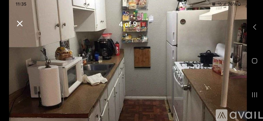 A kitchen with a white microwave, white fridge, and white cabinets.