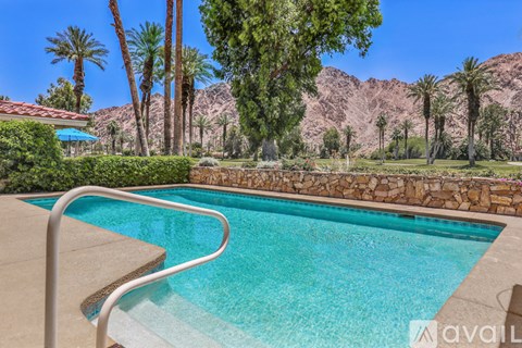 A pool surrounded by palm trees and a mountain in the background.