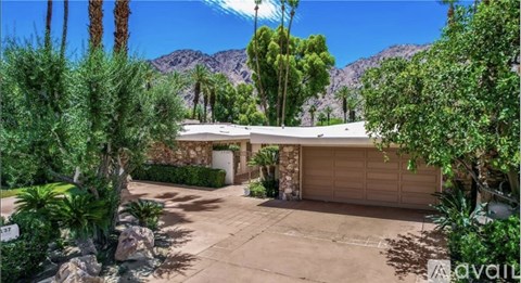 A house with a garage and a mountain in the background.