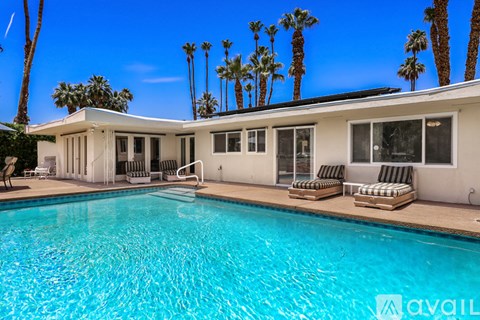 A pool in front of a house with palm trees in the background.
