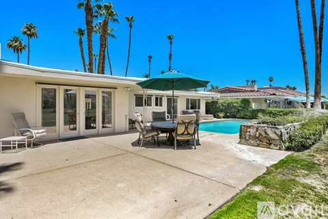 A house with a pool and palm trees in the background.
