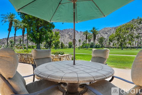 A patio table with a green umbrella and four chairs.