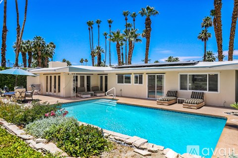 A house with a pool and palm trees in front.