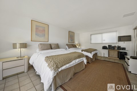 A bedroom with two beds and a small kitchenette.