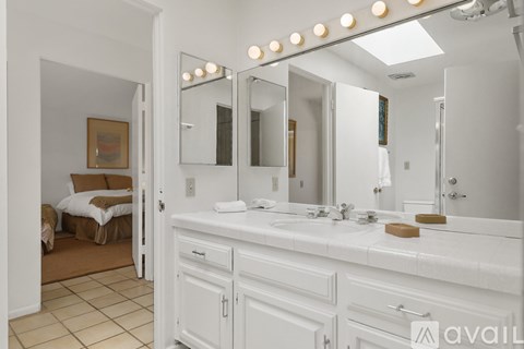 A bathroom with a vanity, a mirror, and lights above it.