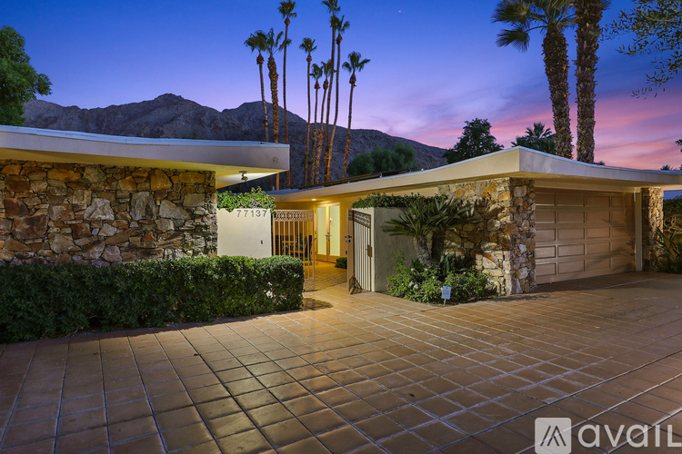 A house with a driveway and palm trees in the background.