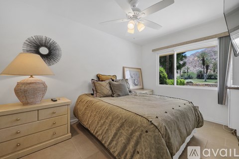 A bedroom with a bed, dresser, and a ceiling fan.