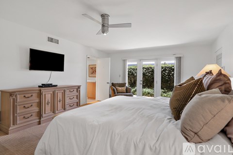 A bedroom with a large bed, a television, and a dresser.