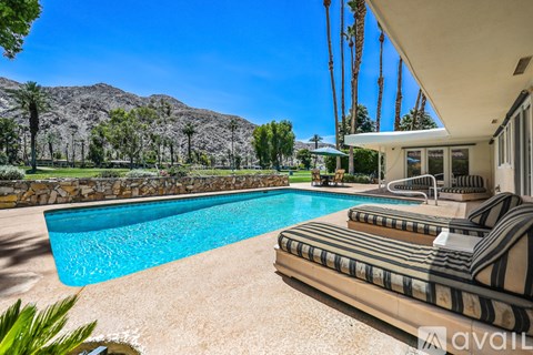 A pool with a striped lounge chair and a mountain in the background.