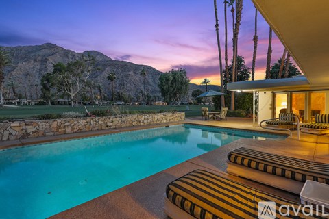 A pool with a mountain in the background at dusk.