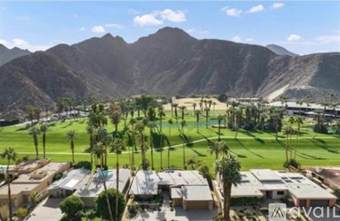 A golf course with a mountain in the background and houses in the foreground.